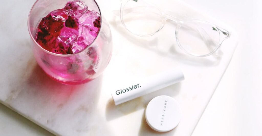 Flat lay of cosmetics with a pink drink on marble – beauty and lifestyle theme.