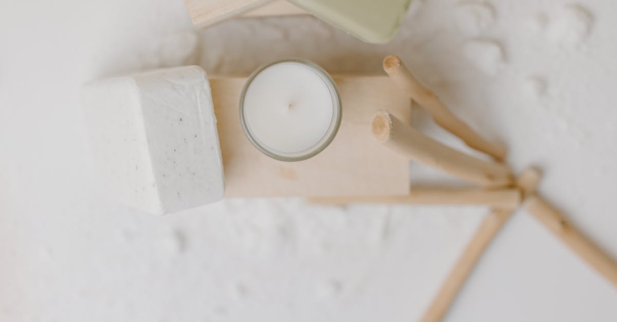 Minimalist flat lay of candle, soap, and wooden skincare tools on a white background representing gentle exfoliation in dry climates.