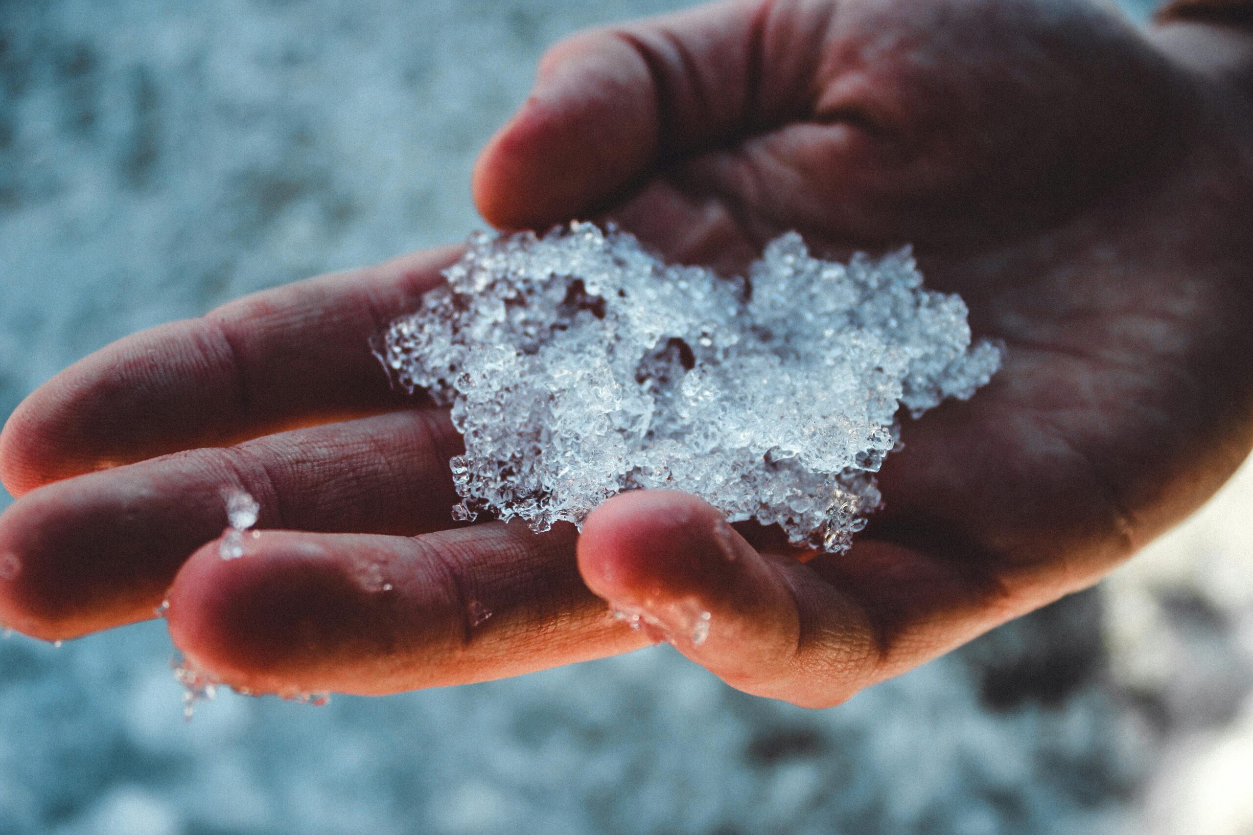 hand holding ice crystals in winter air showing why skincare isn’t working in winter due to cold dry conditions