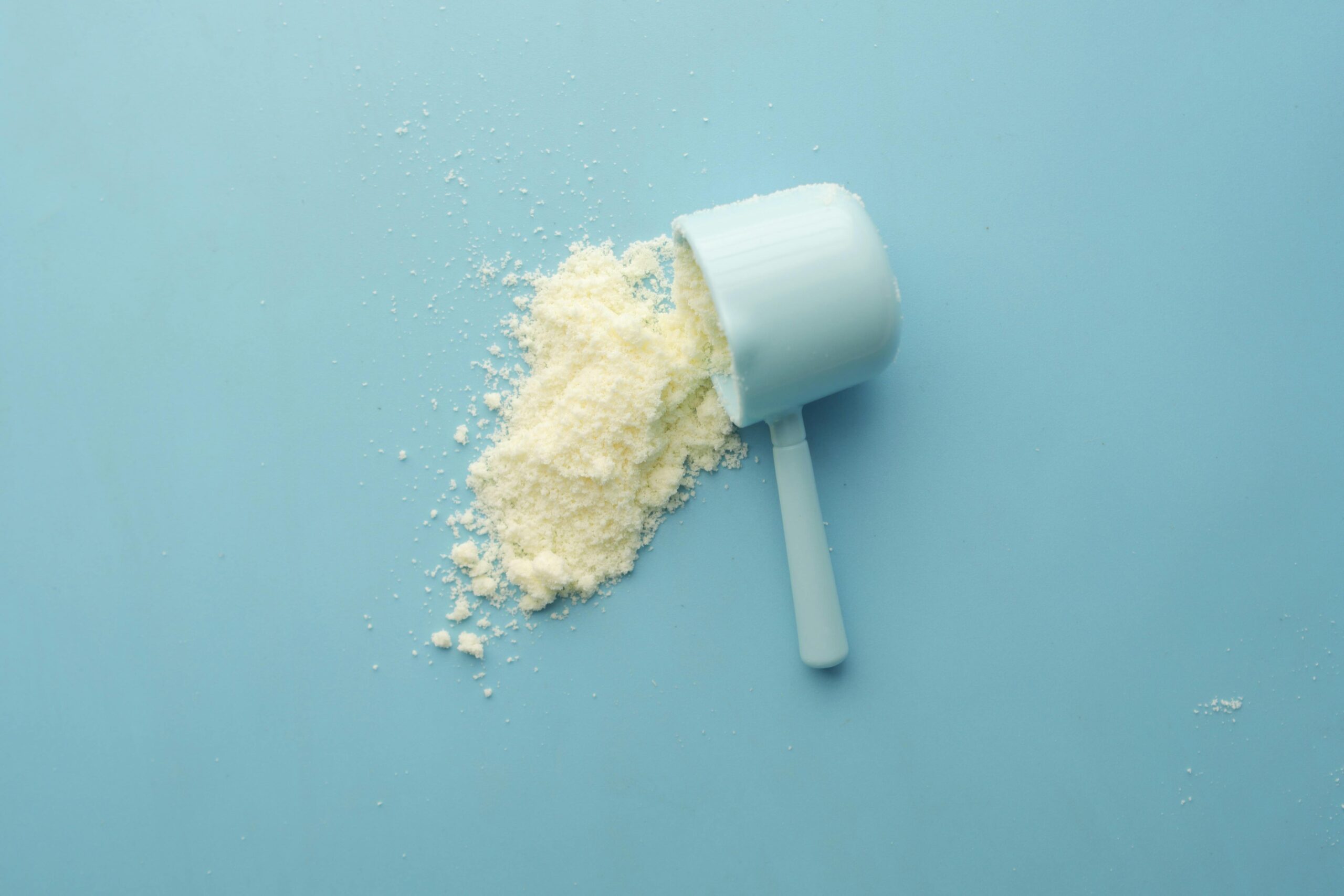 Collagen powder in scoop on blue background – is collagen powder worth it for skin and health