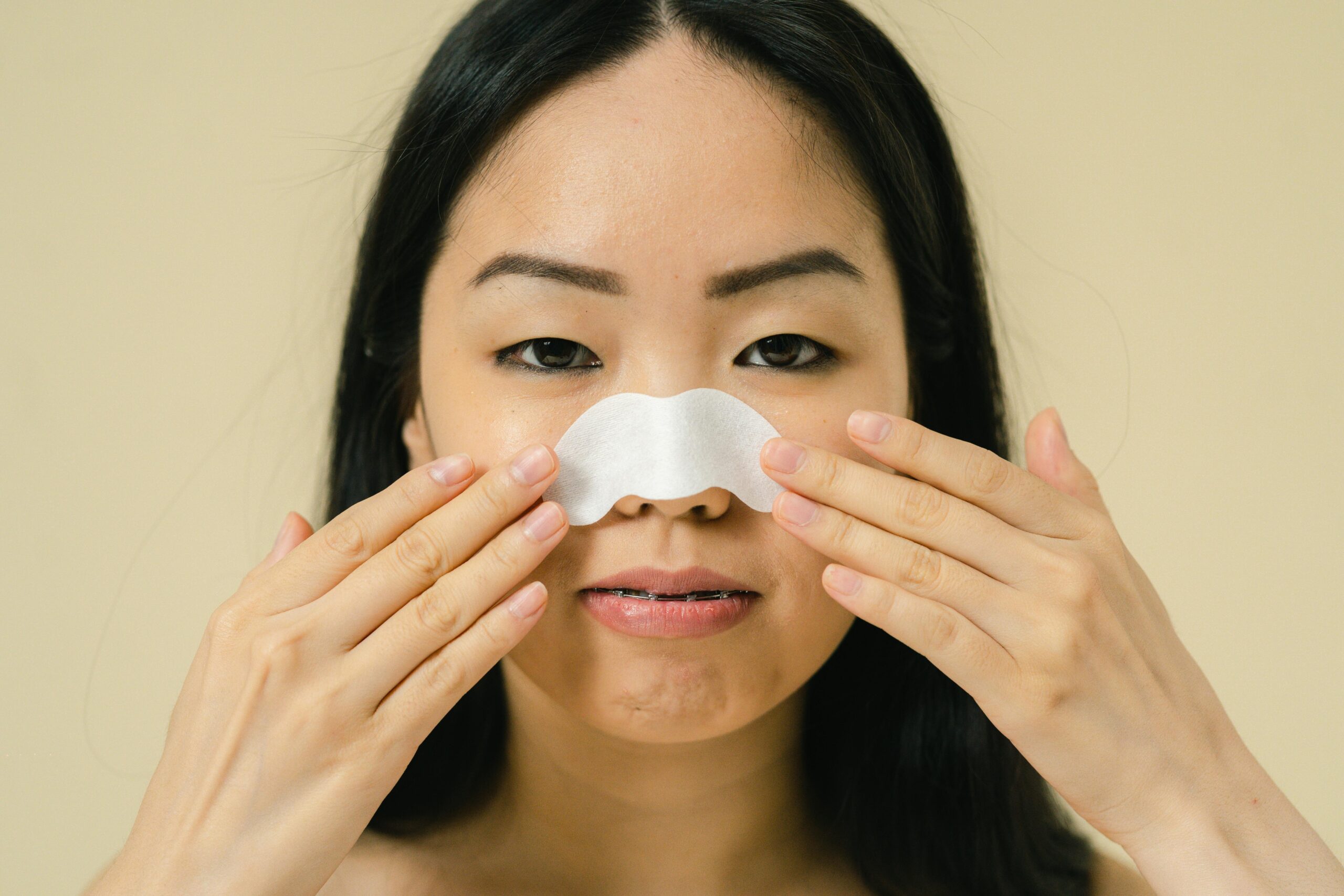 Woman applying a nose strip to her nose – featured image for do nose strips actually work skincare article